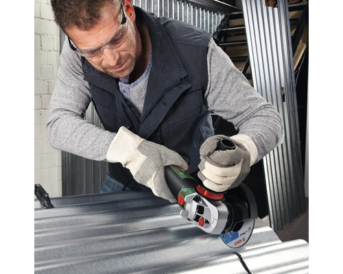 Man met veiligheidsbril en handschoenen snijdt metaal met een haakse slijper.