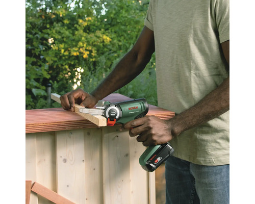 Een persoon gebruikt een Bosch accuschuurmachine om een stuk hout te bewerken.