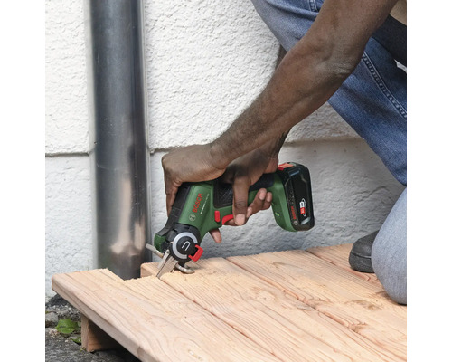 Een persoon zaagt hout met een Bosch accu-multizaag.