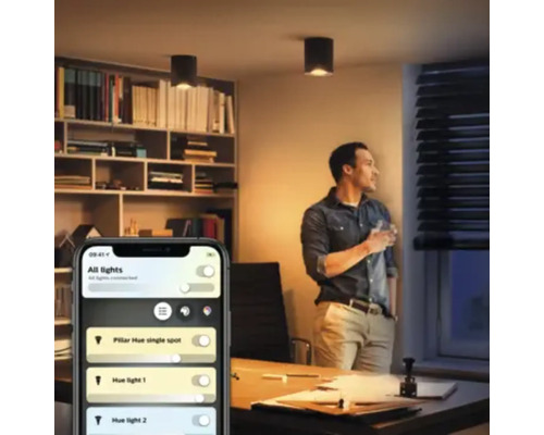 Kantoor scène met een persoon die uit het raam kijkt en een smartphone met een app om lampen te bedienen