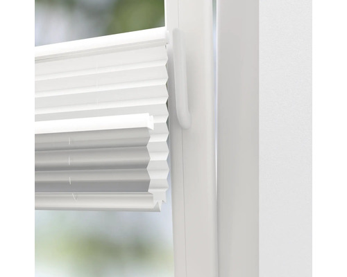 Detail van een wit plisségordijn op een raam