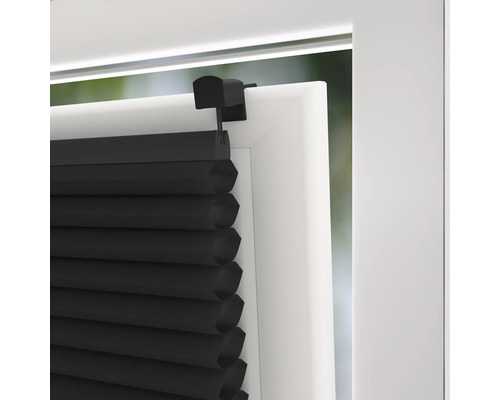 Detail van een zwart plisségordijn op een raamkozijn