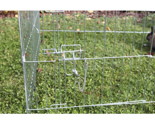 Close-up van een draadkooi met vergrendelingsmechanisme voor kleine dieren in de tuin.