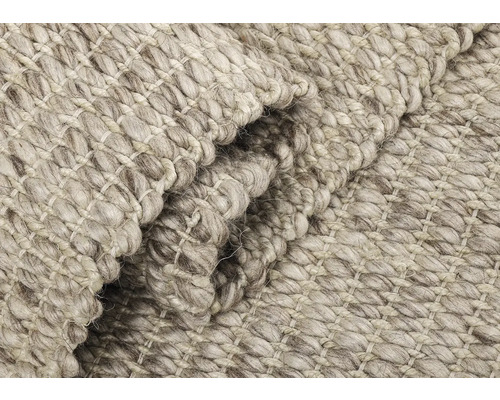 Close-up van een lichtgekleurd tapijt met een grove weefstructuur