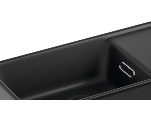 Detailaanzicht van een zwarte gootsteen met overloopgarnituur