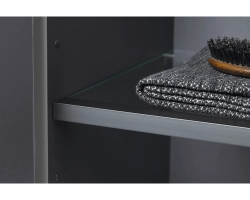 Detailopname van een badkamerkast met glazen plank, handdoek en borstel