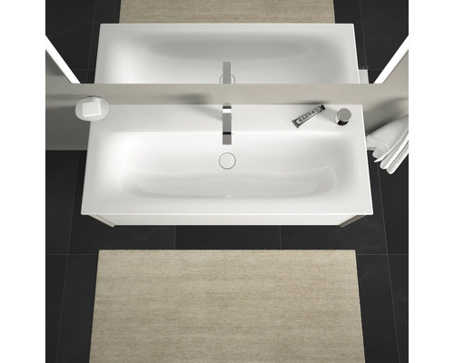 Top-down weergave van een badkamer met wastafel, spiegel, kraan, zeepdispenser, tandpasta, handdoek en badmat