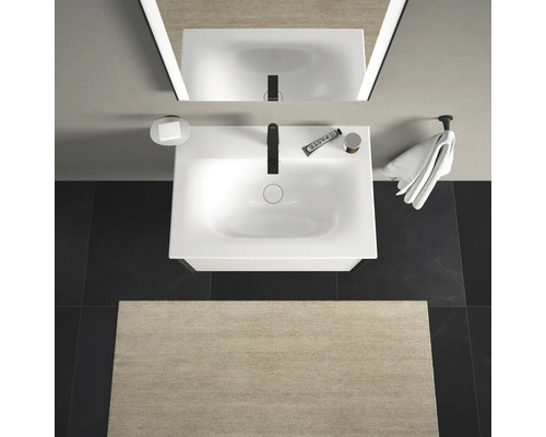 Bovenaanzicht van een badkamer met wastafel, spiegel, handdoek en badmat