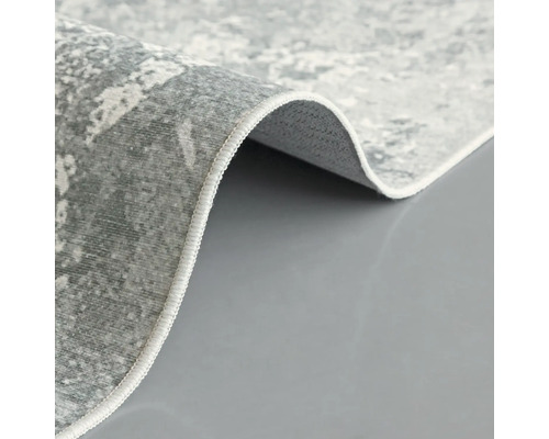 Detailopname van een grijs tapijt met abstract patroon en afgewerkte randen