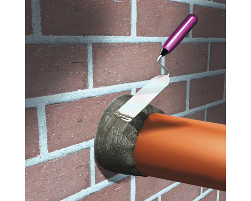 Metselaar vult met een troffel een gat in een bakstenen muur