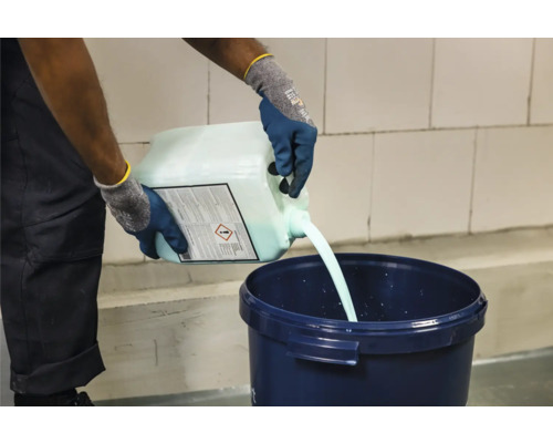 Iemand giet vloeistof uit een jerrycan in een emmer.