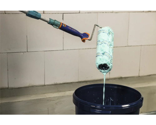 Verf wordt met verfroller in verfemmer afgerold.