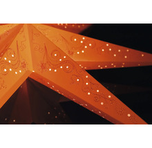Close-up van een verlichte papieren ster met perforaties en decoratieve ornamenten