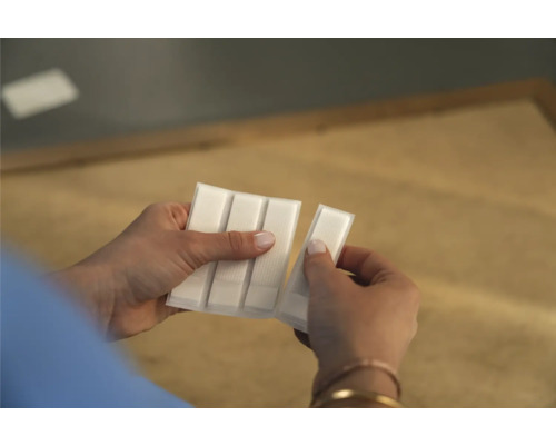 Een persoon houdt een pakje plakstrips in de hand.