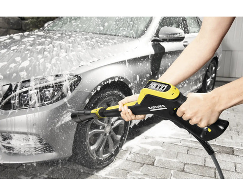 Een auto wordt gewassen met een hogedrukreiniger en schuim.