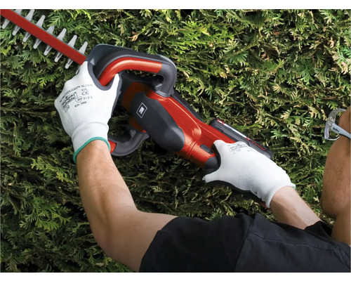 Iemand gebruikt een heggenschaar en draagt beschermende handschoenen.