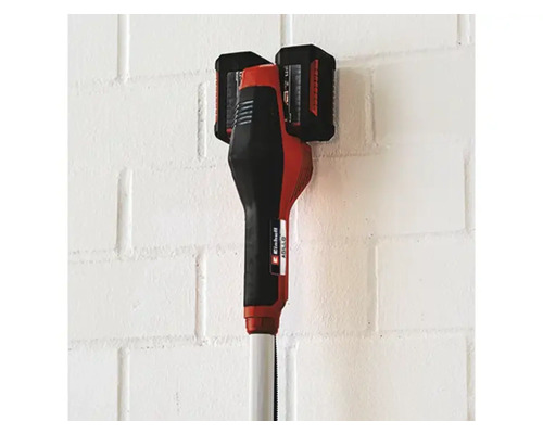 Accu grastrimmer met twee accu's aan een muur