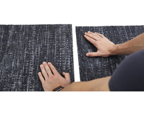 Detailopname van een grijs tapijt met textielpatroon en twee handen