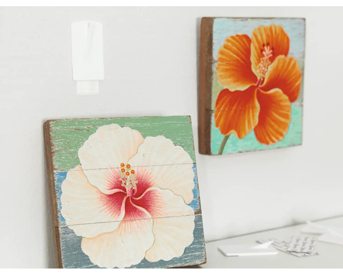 Twee houten schilderijen met bloemmotieven hangen aan de muur