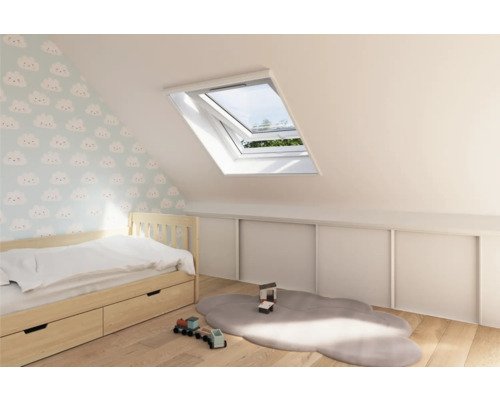 Dakvenster in een lichte kinderkamer met bed en speelgoed