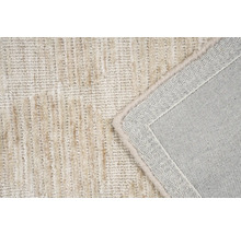 Detail van een beige tapijt met een structuurpatroon en afgewerkte randen.