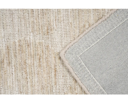 Detail van een beige tapijt met een structuurpatroon en afgewerkte randen.