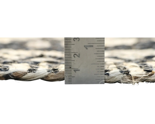 Detailopname van een geweven tapijt met een meetlat om de dikte aan te geven