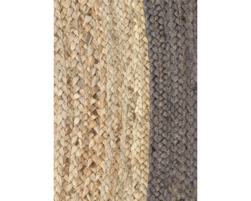 Close-up van een gevlochten tapijt van natuurlijke vezels met verschillende kleursegmenten.