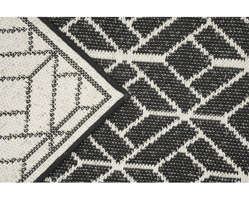 Detail van een zwart-wit buitentapijt met geometrisch patroon.