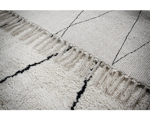 Detailopname van een vloerkleed met franjes en een grafisch patroon