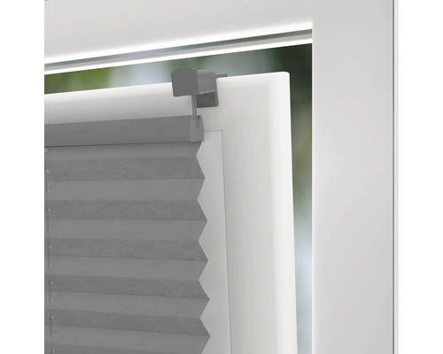 Grijze plisségordijnen op het raam met beugel voor lichtregeling