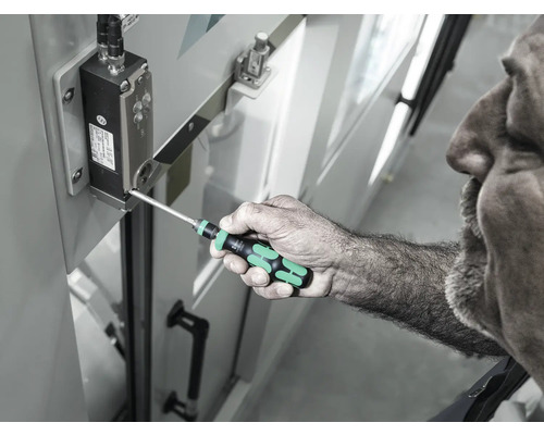 Een man gebruikt een schroevendraaier om een schroef op een elektronisch onderdeel vast te draaien.