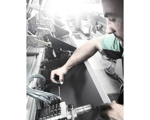 Een man werkt met een schroevendraaier aan een machine.