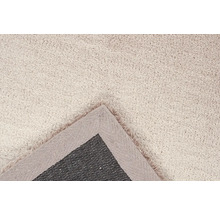 Detail van een beige vloerkleed met franjes