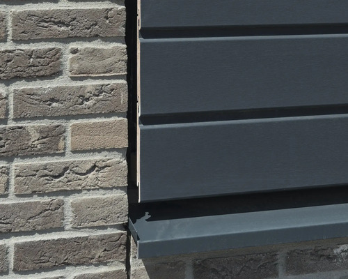 Close-up van een gevel met bakstenen en kunststof panelen