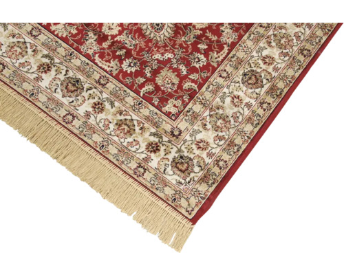 Detail van een rood tapijt met bloemmotief en franjes