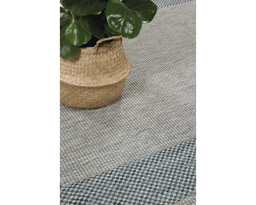 Interieurscène met een gestructureerd vloerkleed en een kamerplant in een mand.