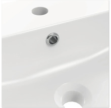 Detailopname van een witte wastafel met kraangat en overloop