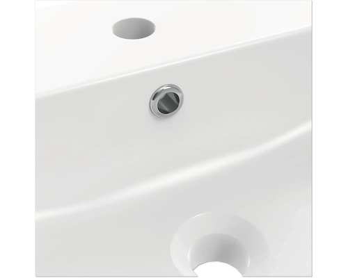 Detailopname van een witte wastafel met kraangat en overloop