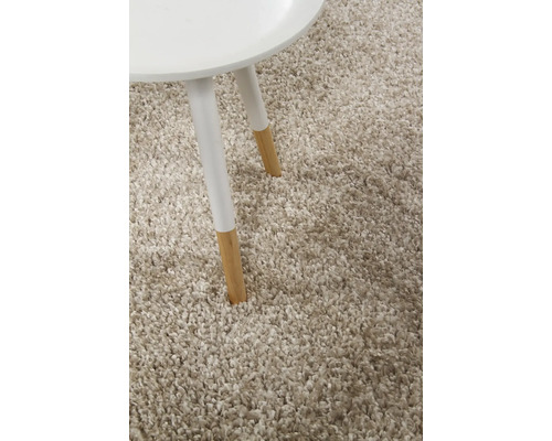 Detailweergave van een beige hoogpolig tapijt met een klein tafeltje