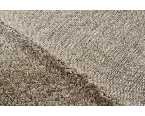 Detailopname van een beige hoogpolig tapijt met geweven achterkant