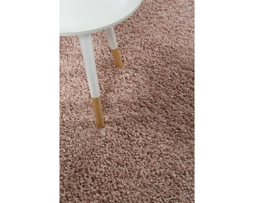 Detail van een hoogpolig vloerkleed naast een tafeltje