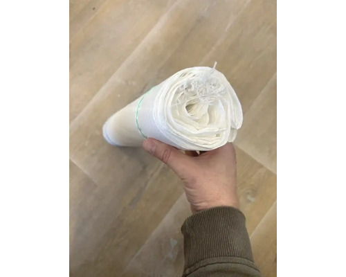 Een rol onkruidvlies wordt in de hand gehouden.