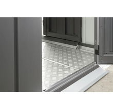 Detailopname van een metalen vloerplaat en een open deur van een tuinhuis