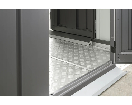 Detailopname van een metalen vloerplaat en een open deur van een tuinhuis