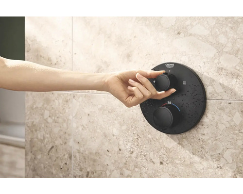 Hand bedient zwarte douchethermostaat van Grohe aan betegelde wand