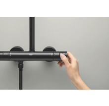 Detailopname van een zwarte douchekraan met een hand die de knop voor de temperatuurinstelling bedient