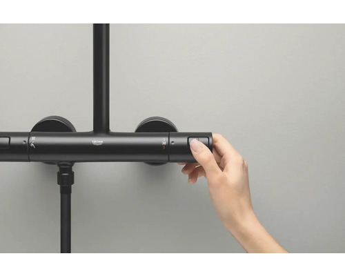 Detailopname van een zwarte douchekraan met een hand die de knop voor de temperatuurinstelling bedient