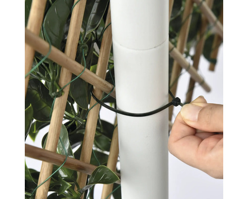 Detailopname van een persoon die een privacyscherm met een kabelbinder aan een paal bevestigt.