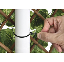 Iemand bevestigt een privacyscherm met een kabelbinder aan een paal.